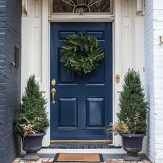 blue front door with wreath and potted trees