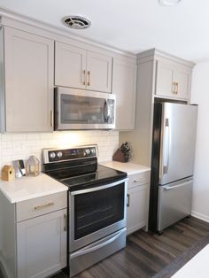 a kitchen with white cabinets and stainless steel appliances, including a stove top oven and refrigerator