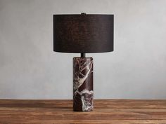 a lamp that is sitting on top of a wooden table with a black shade over it