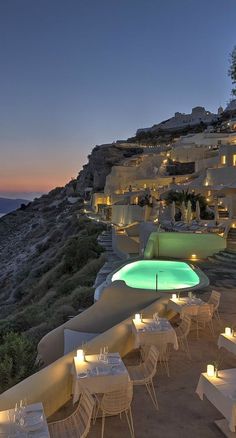 an outdoor dining area with tables and chairs overlooking the ocean at night, lit up by candles