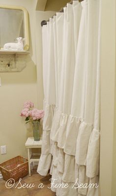 a white shower curtain with ruffles on it in a bathroom next to a mirror