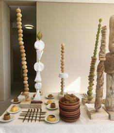 a table topped with lots of different types of wooden sculptures and plates filled with food