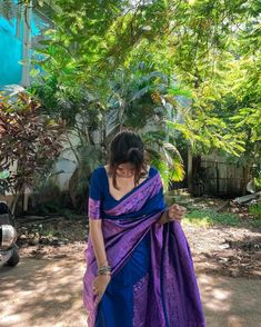 a woman in a blue and purple sari is standing outside with her hands on her hips