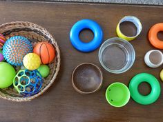 an assortment of colorful plastic toys in a basket on a table with scissors and other items