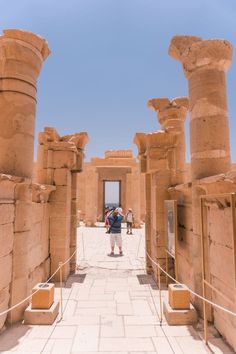 people are standing in front of some very large columns and pillars at the entrance to an ancient city