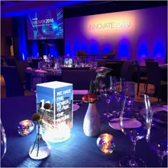 a table set up for an event with wine glasses and vases on the table