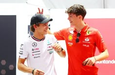 two men standing next to each other on top of a race track with one pointing at the other