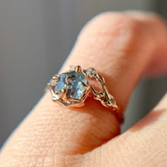 a close up of a person's hand wearing a ring with an aqua blue stone