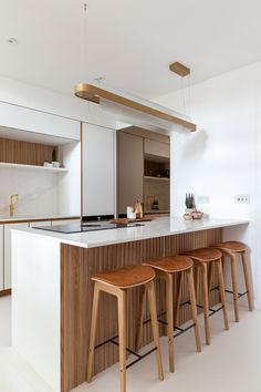 three stools are sitting at the bar in this modern kitchen with white walls and cabinets