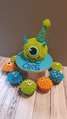 there is a birthday cake with cupcakes in the shape of monsters