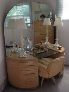 a table with two lamps and a mirror on it in front of a window next to a dresser