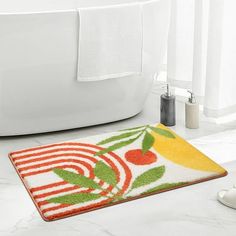 a bathroom rug with fruit on it next to a bath tub