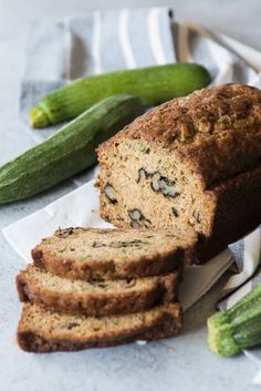 a loaf of zucchini bread sitting on top of a table next to cucumbers