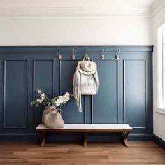 a bench with a hat, coat rack and flowers on it next to a window