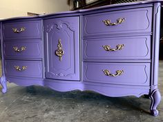 a purple dresser with gold handles in a room