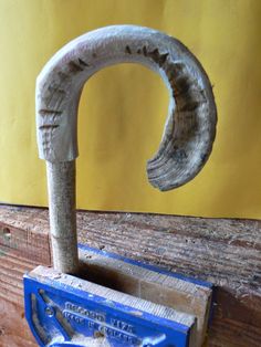 an old metal hook with a wooden handle attached to it on a piece of wood