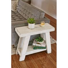 a small table with a plant on it in front of a couch and coffee table