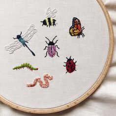 a close up of a embroidery on a white cloth with bugs and insects in it