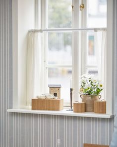 a window sill with flowers and candles on it in front of a striped wall