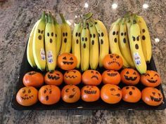 oranges and bananas with faces drawn on them are arranged in a display case for halloween