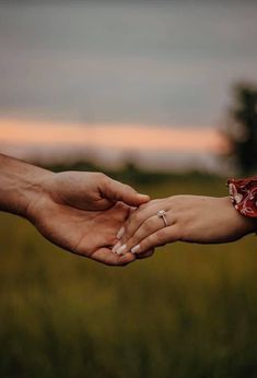 two people holding each other's hands in a field