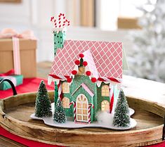 a paper house on a tray with christmas decorations