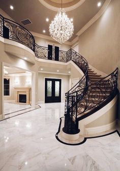 a large foyer with marble flooring and chandelier above the stairs is shown