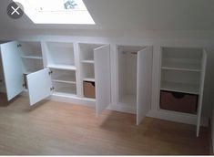 an empty room with white shelves and skylight