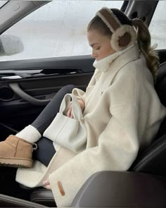 a woman sitting in the back seat of a car wearing headphones and holding a purse