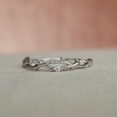 a close up view of a wedding ring with branches and flowers on it, sitting on a surface