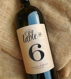 a bottle of wine sitting on top of a cloth covered tablecloth with the number five printed on it