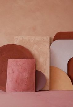 several different shapes and sizes of plates against a pink wall