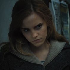 a young woman with long hair and blue eyes stares at the camera in a dark room