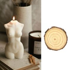 a white candle sitting on top of a book next to a wooden slice with a candle in it