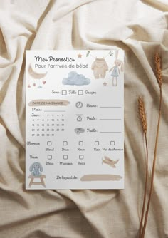 a calendar with animals on it sitting on a bed next to some dry grass and a plant