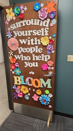 a door decorated with paper flowers and the words, surround yourself with people who help you bloom