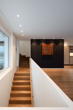 an empty room with stairs leading up to the second floor and a painting on the wall