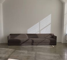 a couch sitting in the middle of a room next to a window with sunlight streaming through it