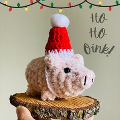 a stuffed animal wearing a knitted santa hat on top of a piece of wood