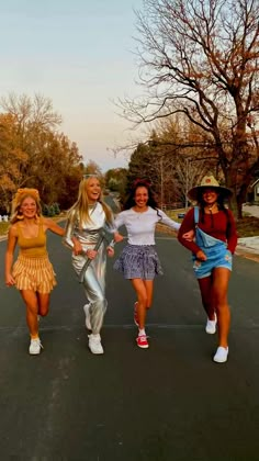 four girls are walking down the street together