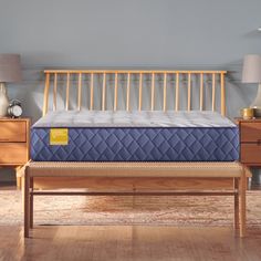 a blue mattress sitting on top of a wooden bed frame next to a night stand