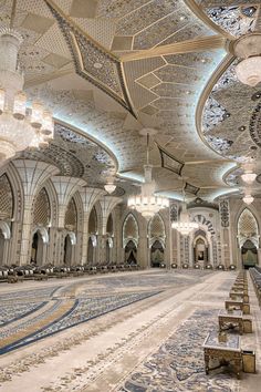 an ornately decorated hall with chandeliers and benches in front of the ceiling