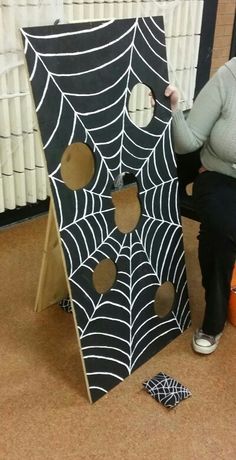 a woman sitting on the floor next to a black and white spider web door decoration