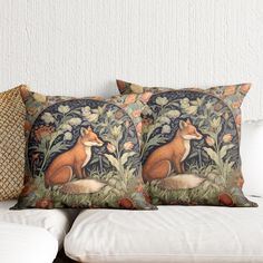 two pillows with foxes on them sitting on a couch