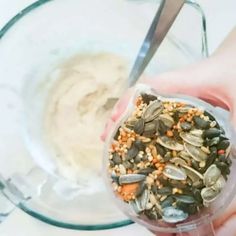 a person is scooping seeds into a glass bowl