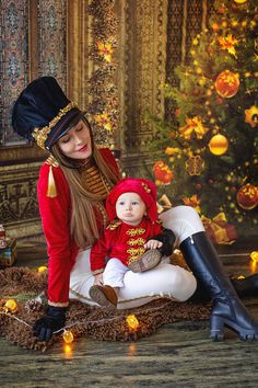 a woman and her baby dressed up in costumes sitting on the floor next to a christmas tree