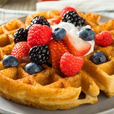 a waffle topped with berries and whipped cream