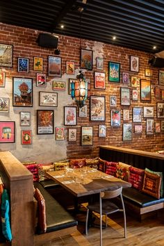 the interior of a restaurant with many pictures on the wall and wooden tables in front of it