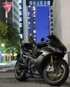 a black motorcycle parked on the street in front of some tall buildings at night time