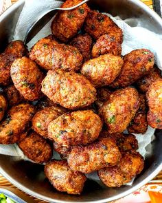 a bowl filled with meatballs sitting on top of a table next to other food items